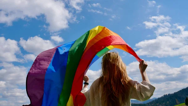 Frau mit LGBT-Flagge auf Himmelshintergrund — Stockfoto