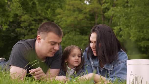 Familia feliz relajándose en la naturaleza y jugando con un juguete Pop It — Vídeo de stock