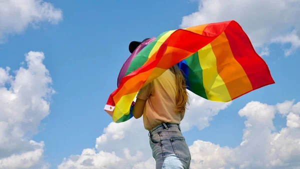 Gökyüzü arka planında LGBT bayrağı tutan lezbiyen — Stok fotoğraf