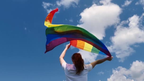En person håller en hbt-flagga och dansar i stolthetens månad — Stockvideo