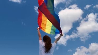 Woman from the back holds an LGBT flag