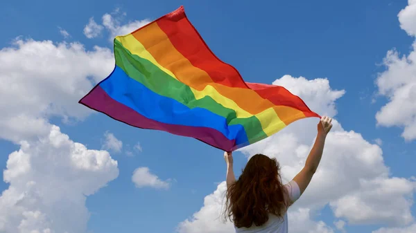 Pessoa de trás detém uma bandeira LGBT — Fotografia de Stock