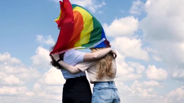 Lesbiska kramar och håller en hbt-flagga — Stockvideo
