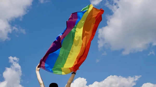 Gökyüzü arka planında LGBT bayrağı tutan kişi — Stok fotoğraf