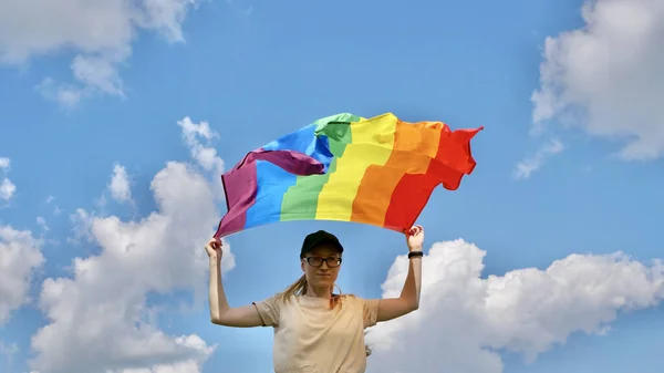 Человек, держащий флаг ЛГБТ на фоне неба — стоковое фото
