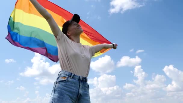 Бисексуальная женщина с флагом ЛГБТ на фоне неба — стоковое видео