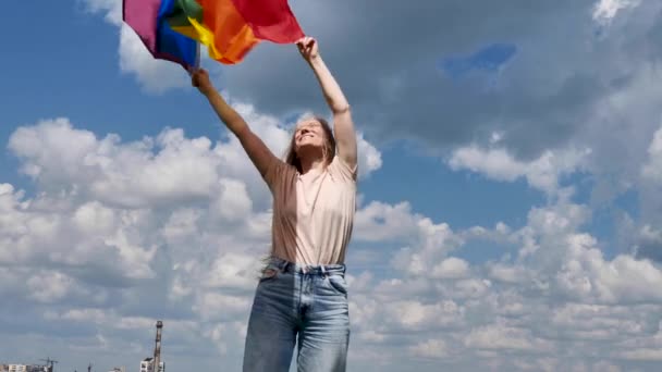 Bisexuell kvinna som håller hbt flagga på himlen bakgrund — Stockvideo