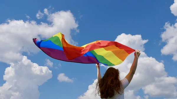 Person hålla hbt flagga på himlen bakgrund — Stockfoto