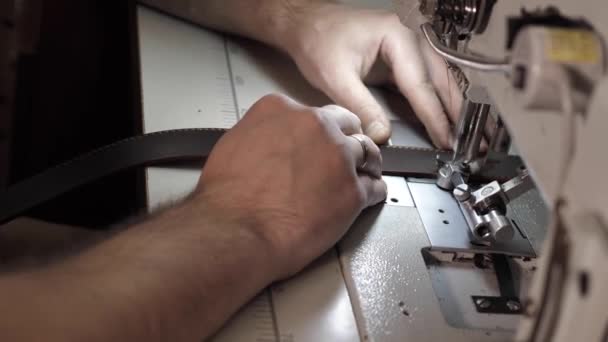 Человек пришивает кожаный ремень к швейной машинке — стоковое видео