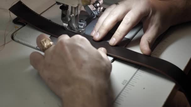 Man naait een lederen riem op een naaimachine — Stockvideo