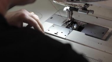 Adam dikiş makinesine deri kemer dikiyor.