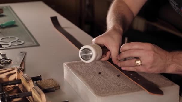Hombre hace un cinturón de cuero en el taller — Vídeos de Stock