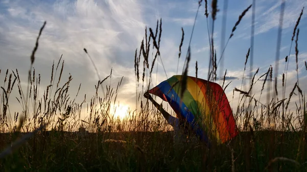 日落天空背景上挂着LGBT旗的女人 — 图库照片