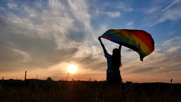 日落天空背景上挂着LGBT旗的女人 — 图库照片