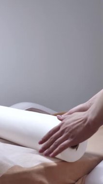 Bir masaj ya da tıbbi tedavi yatağını örtmek için temiz ve hijyeni vurgulayan yeni, beyaz bir kağıt çarşaf saran profesyonellerin yakın çekimi..