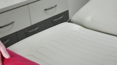 Bir tüy dökücü uzmanı, hemşire bir müşteri için pembe bir tek kullanımlık çarşaf serer. Yakın plan, yüzü yok.