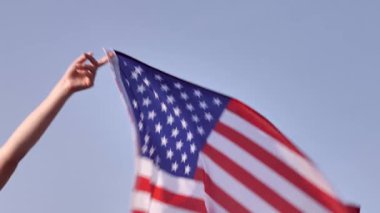 Amerikan bayrağı açık gökyüzüne karşı dalgalanır, Amerikan özgürlüğünü ve vatanseverliğini simgeler. Anayasa Günü ve ulusal gurur için mükemmel.