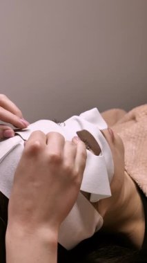 Bir güzellik uzmanının elleri, bir kadının yüzüne hidratasyon maskesi takar. Bu resim güzellik ve rahatlama için profesyonel bir spa tedavisini yakalar.