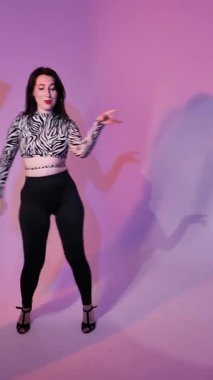 Bachata Lady Style on neon purple background lighting, Young brunette Caucasian woman dancing feminine choreography. vertical, general close-up
