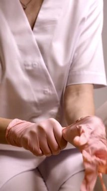 Bir profesyonel, klinik, tıbbi ya da güzellik ortamında güvenlik ve hijyeni vurgulamak için pembe tek kullanımlık eldiven takar.