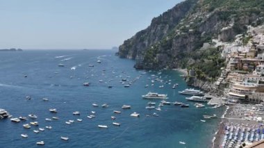Scenic panoramic view Amalfi town on Coast, Italy. Colorful houses, church tower, marina with boats along Mediterranean Sea, surrounded by steep cliffs and green hills. Italian Riviera UNESCO World