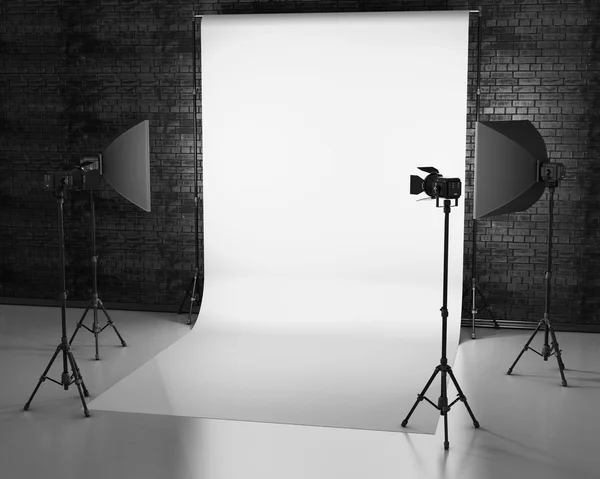 Fundo branco iluminado com equipamento de estúdio contra uma parede de tijolo . — Fotografia de Stock