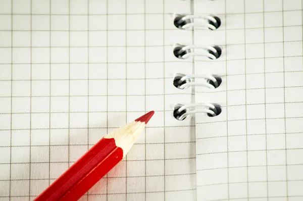 Red pencil on a background of the disclosed notepad. — Stock Photo, Image