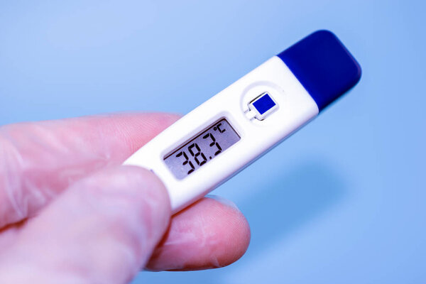 Digital body thermometer in human hands display temperature.