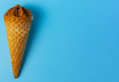 Mavi parlak arkaplanda koni şeklinde karamel dondurması..