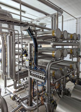 Paslanmaz çelik borular, kıskaçlar ve esnek hortumlardan oluşan karmaşık bir ağ süt filtreleme için yüksek hassasiyetli bir üretim sistemi oluşturur..