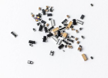 Yüzeye saçılmış elektronik bileşenler beyaz bir arkaplanda yakından çekilmiş, kapasitörler, rezistanslar ve diyotlar gösteriliyor. Elektronik imalat, onarım, mühendislik ve teknoloji kavramları için ideal.