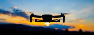 Drone silhouette at sunset time clipart