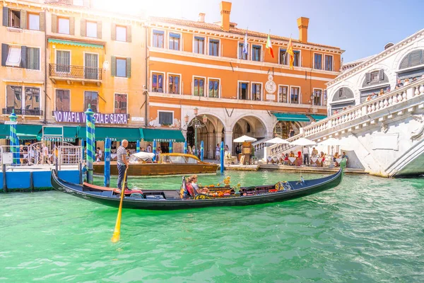 VENECIA, ITALIA - 02 DE AGOSTO DE 2021: Turistas y gondoleros en góndola. Romántico crucero en góndola en el canal de agua veneciano cerca del Puente de Rialto, Venecia, Italia — Foto de Stock