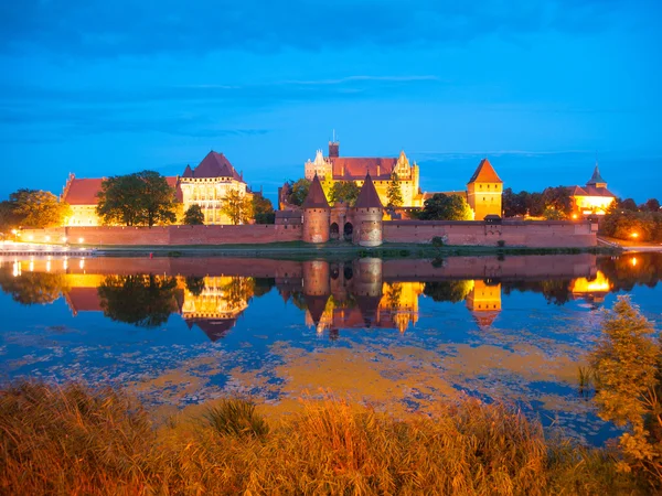 Castillo de Malbork por la noche con reflejo en el río Nogat — Foto de Stock