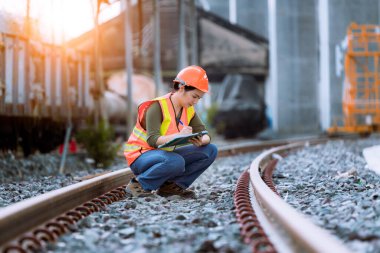 Portre mühendisi teftiş altında ve inşaat sürecini kontrol ediyor ve tren istasyonunda çalışmalarını kontrol ediyor. İş yerinde güvenlik üniforması ve güvenlik kaskı takan mühendis.
