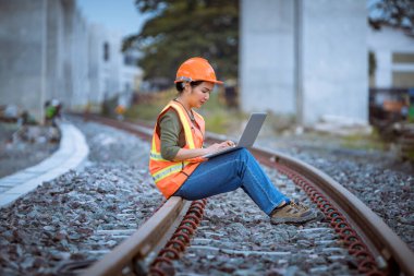 Portre mühendisi teftiş altında ve inşaat sürecini kontrol ediyor ve tren istasyonunda çalışmalarını kontrol ediyor. İş yerinde güvenlik üniforması ve güvenlik kaskı takan mühendis.
