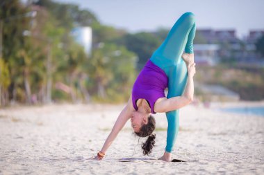 Spor kadını sabah kumsalda yoga egzersizi yapıyor. Yoga meditasyon ve sağlıklı spor konsepti..