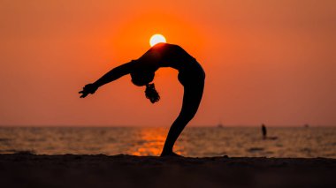 Siluet spor kadını sabah kumsalda yoga egzersizi yapıyor. Yoga meditasyon sağlık sporu konsepti..