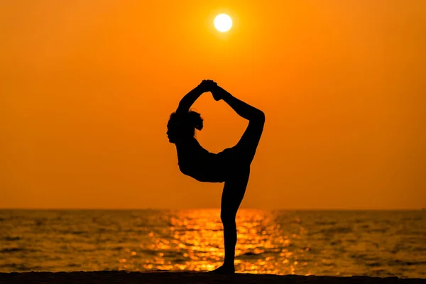 Silhouette sport woman pose practice yoga exercise on sand beach in morning , yoga is meditation heathy sport concept.