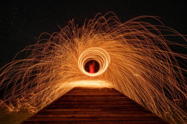 Ateş dansı, gece vakti karanlık gökyüzünde sallanan ışık efektlerini gösterir..