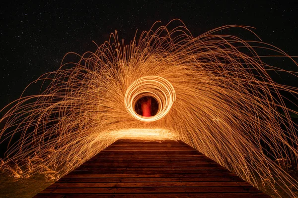 Ateş dansı, gece vakti karanlık gökyüzünde sallanan ışık efektlerini gösterir..