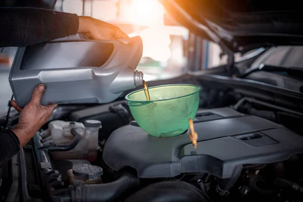 Car mechanic open car hood repairs  checking oil motor level for refill new oil in car garage service and maintenance.