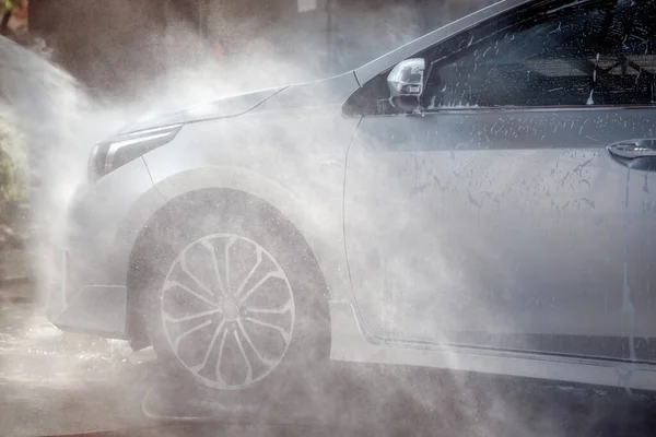 Worker in car wash shop under working to clean customer car by soap form, car service concept.