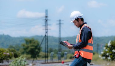 Demiryolu inşaatı, tren testleri ve tren istasyonundaki demiryolu çalışmalarını telsiz iletişimiyle kontrol ediyor. İş yerinde güvenlik üniforması ve güvenlik kaskı takan bir mühendis..