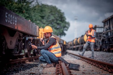 Mühendis teftiş altında ve inşaat sürecinde demiryolu şalterini kontrol ediyor ve tren istasyonundaki işi kontrol ediyor. İş yerinde güvenlik üniforması ve güvenlik kaskı takan bir mühendis..