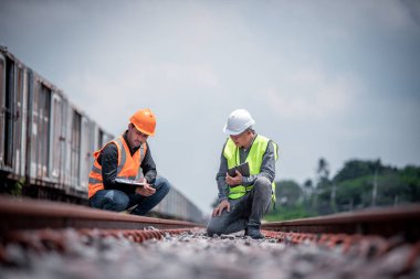 Mühendis teftiş altında ve inşaat sürecinde demiryolu şalterini kontrol ediyor ve tren istasyonundaki işi kontrol ediyor. İş yerinde güvenlik üniforması ve güvenlik kaskı takan bir mühendis..