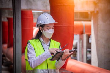 Endüstri soğutma kulesi klimasını kontrol altında tutan mühendis, hava kirliliğini korumak için maske takan, büyük endüstriyel binanın soğutma kulesi soğutma soğutma soğutma soğutma soğutma soğutma soğutma havalandırması havalandırması..