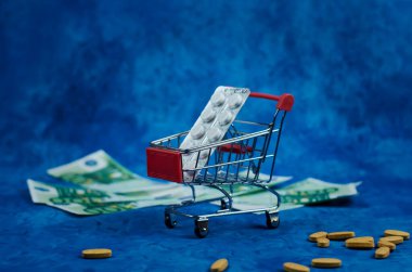 Bakkal sepetindeki su toplayan haplar. Arka planda para, mavi arka plan.