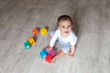 Bebek bloklarla oynuyor. Evde beyaz elbiseli küçük bir çocuk var. Bir bebeğin güzel portresi. Koca gözlü bebek. Uzaktan eğitim. Uzaktan öğrenme