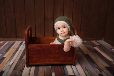 Oyuncak yatakta yeni doğmuş şirin bir bebek. Karanlık arka planda gülümseyen bir bebek. Yeni doğan bebeğin yakın plan portresi. Bebek eşyaları paketleme şablonu. Çocuk odası. Tıbbi ve sağlıklı konsept.